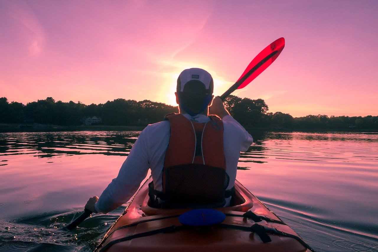 man sitting in kayak during sunset